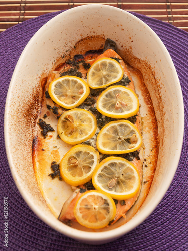 Baked salmon fillet in casserole, topped with lemon slices