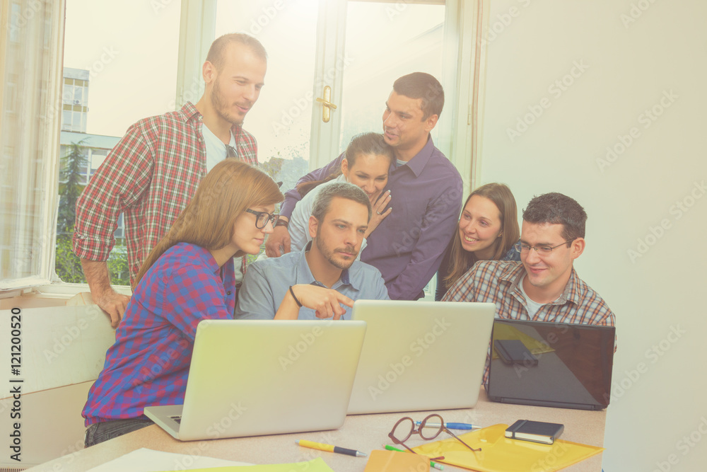 Young group of people discussing business plans, with lap-tops, plans in a small office. Young group of people discussing business plans, with lap-tops, plans in a small office.