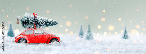 czerwony-samochod-wiozacy-choinke-w-snieznym-lesie