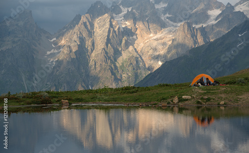 Orange camp  and tourists near mountain lake
