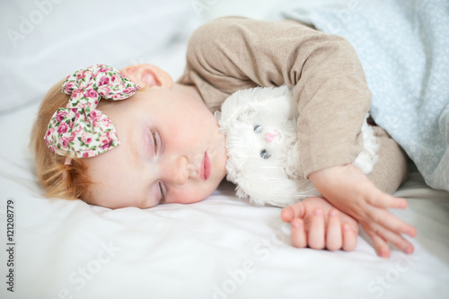 Red-haired girl is sleeping with a soft toy