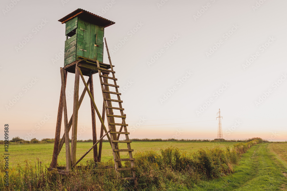 Wooden Hunting high tower on the meadow. Hunters lookout tower.