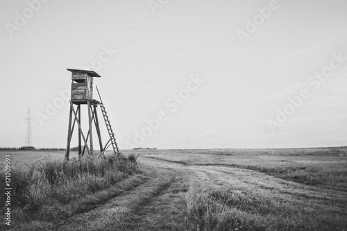 Wooden Hunting high tower on the meadow. Hunters lookout tower.