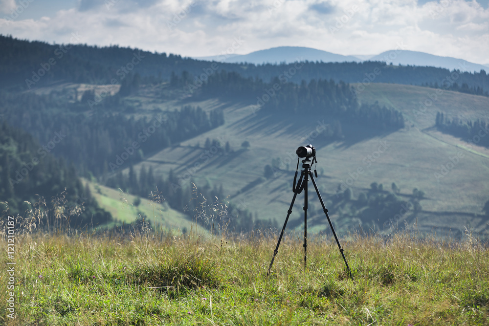 Camera and tripod on the background of mountain scenery