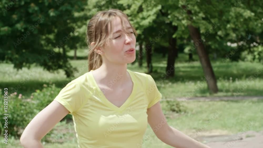 Young woman standing in the park and talking to her friends about something Young woman standing in the park and talking to her friends about something