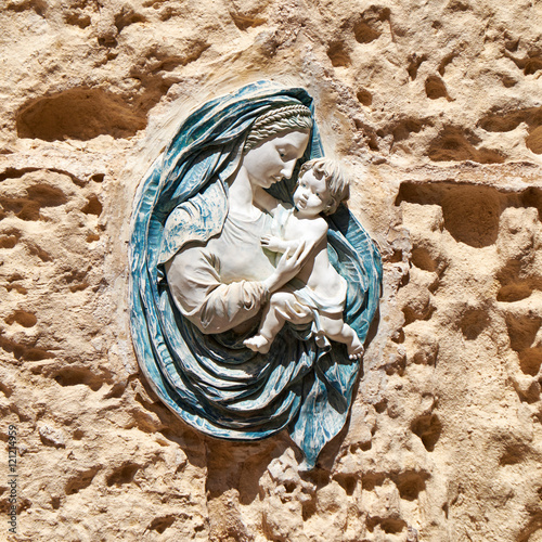 The relif of the Virgin Mary with Child on the building wall in photo