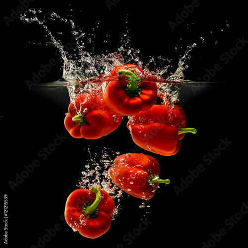 Group of bell pepper falling in water with splash on black background photo