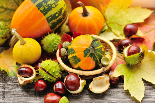 Fresh chestnuts with autumn leaves and mini pumpkins on wooden background
