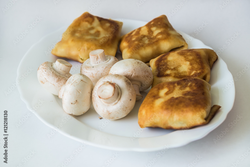 Fried pancakes with fillings and mushrooms in the white plate on a white background Fried pancakes with fillings and mushrooms in the white plate on a white background