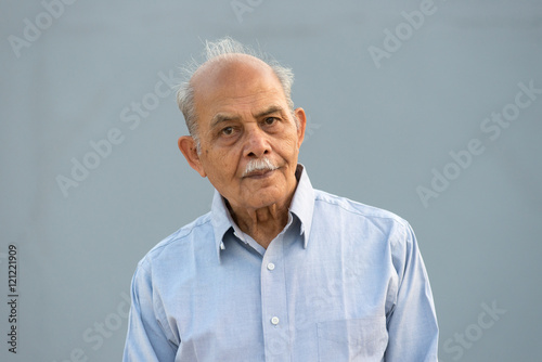 A senior Indian / South Asian man against a light blue background