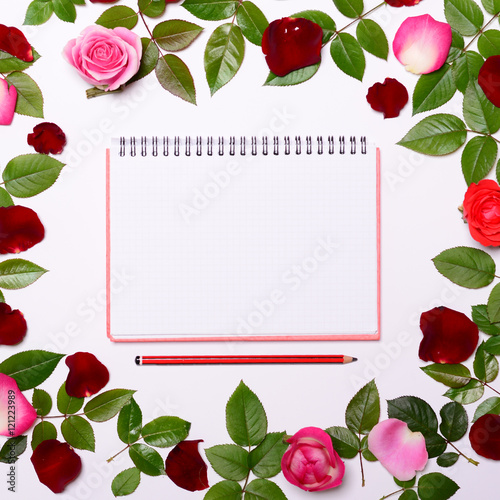Flat lay - Frame made of rose leaves and roses with blank notebo
