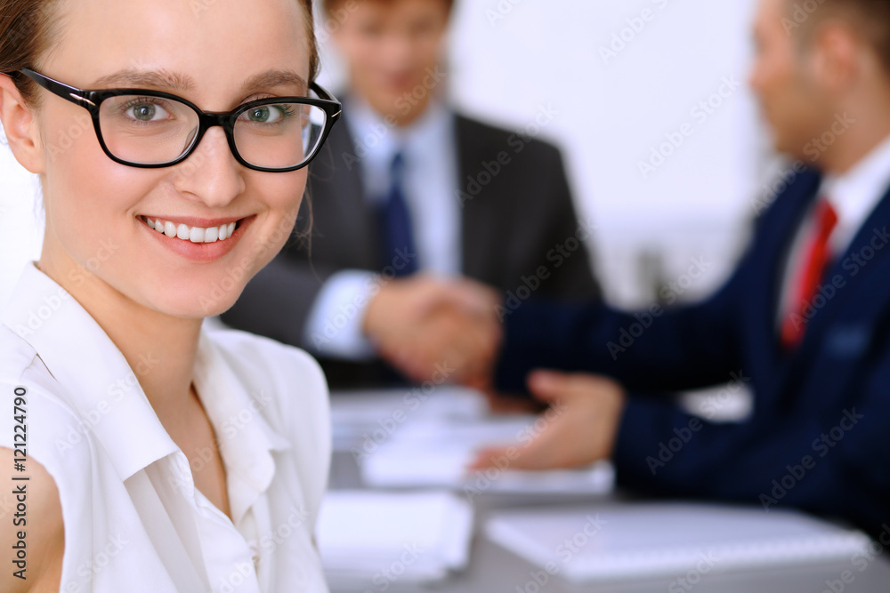Portrait of a young business woman against a group of business people at a meeting. Portrait of a young business woman against a group of business people at a meeting.