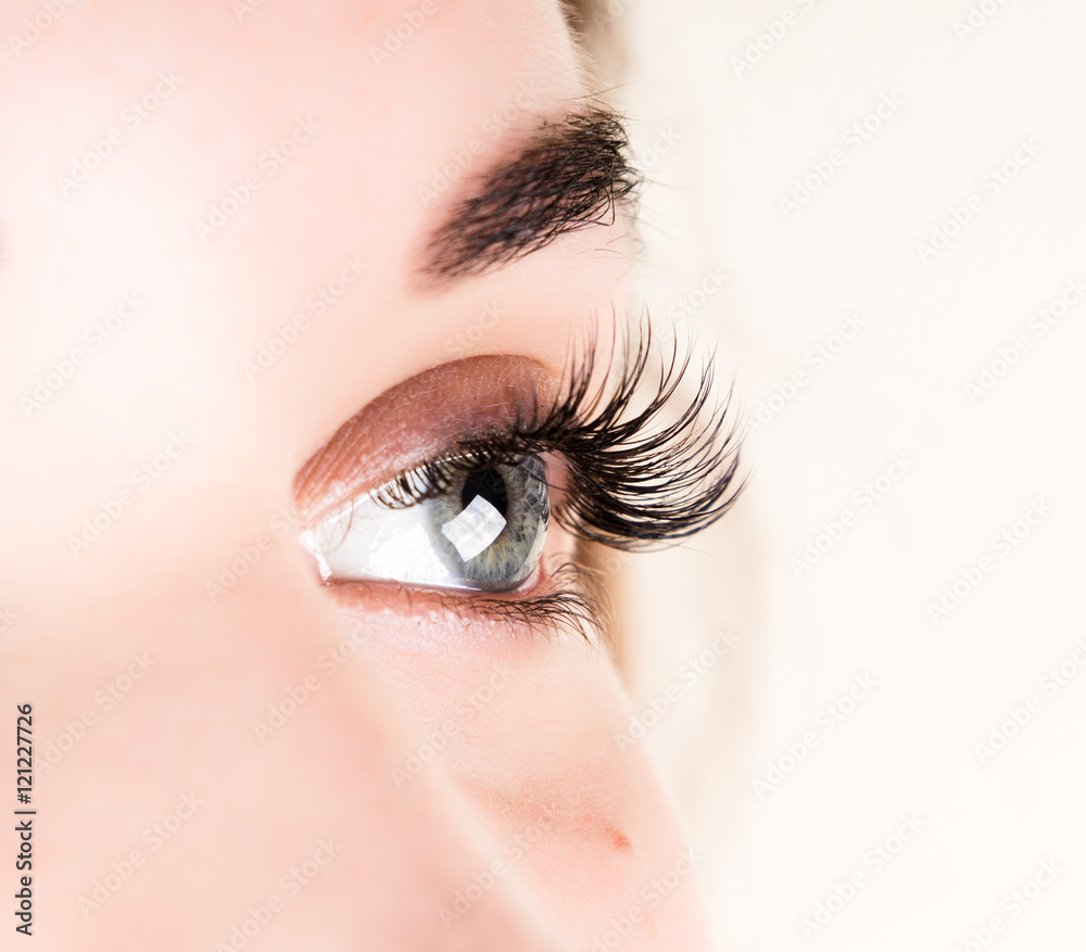 Fototapeta premium Beautiful young girl eyelash extension. Woman eye with long eyelashes. Beauty salon concept