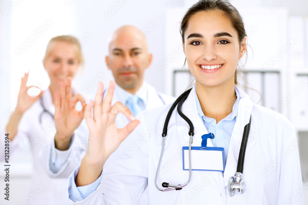Happy doctor woman with medical staff at the hospital. Thumbs up and Ok sign! Happy doctor woman with medical staff at the hospital. Thumbs up and Ok sign!