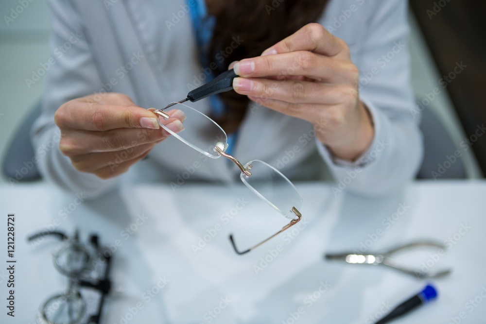 Optician repairing spectacles with tool Optician repairing spectacles with tool