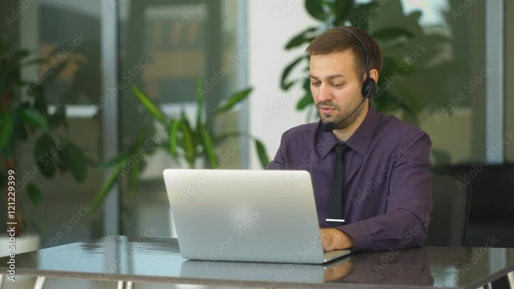 Smiling businessman with headset interacting in his office Smiling businessman with headset interacting in his office