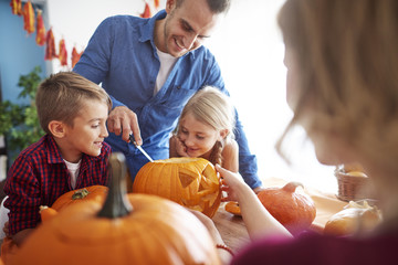 Father helping in drilling pumpkins