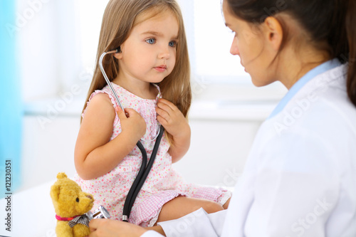 Little doctor examining a .toy bear patient by stethoscope