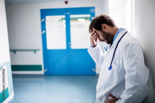 Sad doctor leaning against the wall