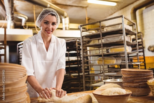 Foto Female baker kneading a dough