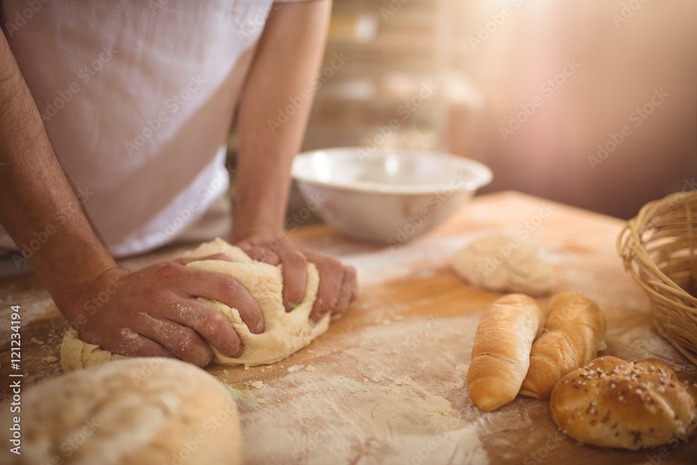 Mid-section of baker kneading a dough