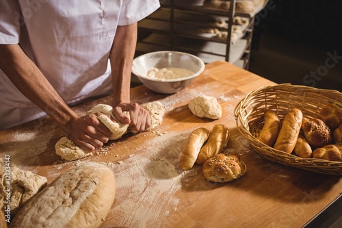 Fototapeta Mid-section of baker kneading a dough