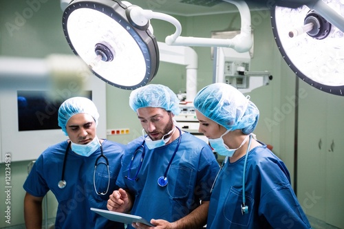 Surgeons discussing over digital tablet in operation room