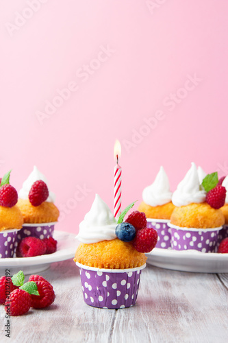 Birthday vanilla cupcakes with fresh raspberries, pink background