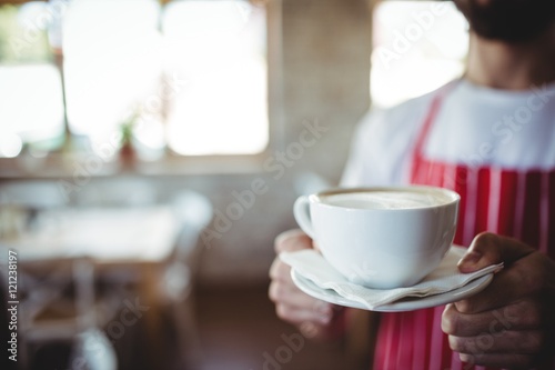 Mid-section male baker holding a cup of coffee