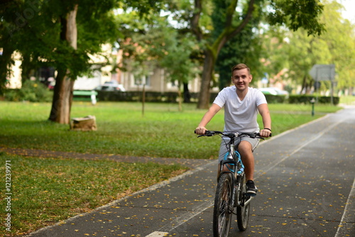 Blonde attractive young man cycling in the park 