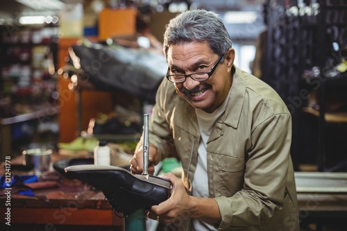 Portrait of smiling shoemaker hammering on a shoe photo