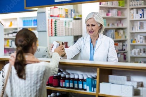 Pharmacist giving medicine box to customer