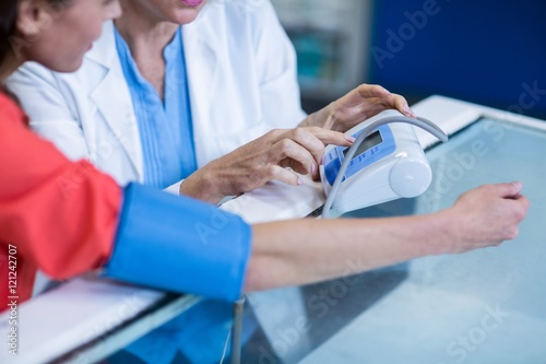 Pharmacist checking blood pressure of customer