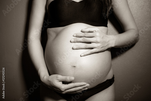 Black and white image shows a pregnant woman standing body.