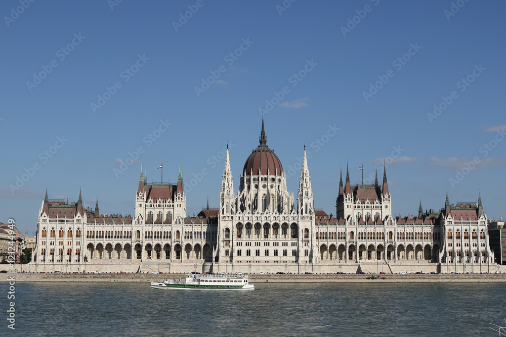 Neo-Gothic building of Hungarian Parliament, a cruise ship on the River Danube in sunlight, Budapest