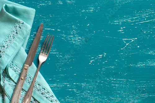 Vintage fork and knife on napkin on turquoise wood