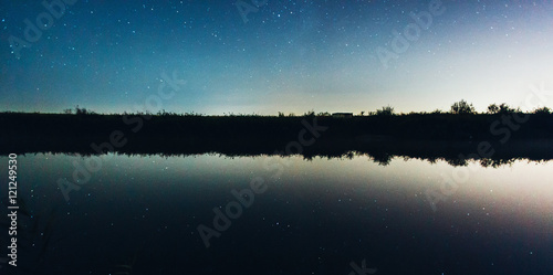 Starry night sky reflected in lake