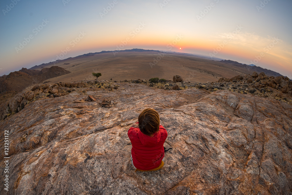 Tourist watching the stunning view of barren valley in the Namib desert, among the most important travel destination in Namibia, Africa. Fisheye view at sunset.