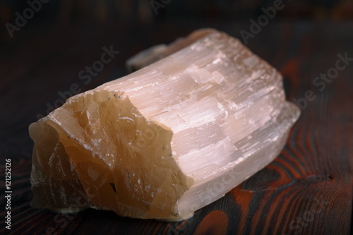 Crystal of Selenite isolated on wooden background photo