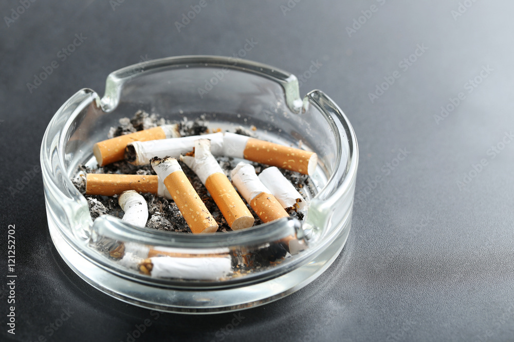 Cigarette butts with ash in ashtray on black background Cigarette butts with ash in ashtray on black background