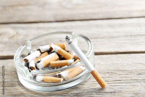 Cigarette with ash on grey wooden table
