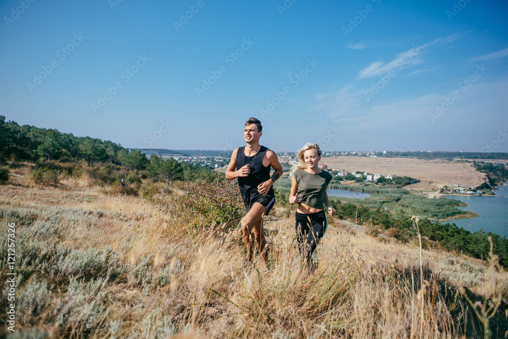 Young couple running outdoor. Male and female jogging in the countryside near the lake