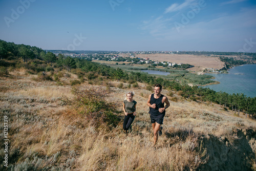 Young couple running outdoor. Male and female jogging in the countryside near the lake