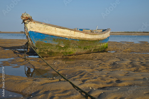 Old wooden fishing boat resting on the beach sand in Portugal