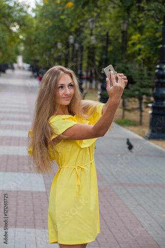 beautiful girl in a yellow dress photographed themselves on the background of the city