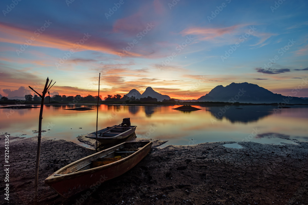 Beautiful majectic sunrise by the lakeside with fishing boats. Nature landscape.
