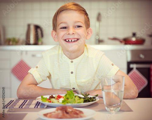 Young diligent happy boy  at a table eating healthy meal with cu
