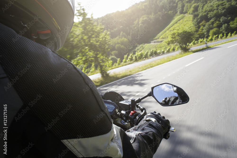 Naklejka premium Motorradfahrer fährt auf Straße im Sommer