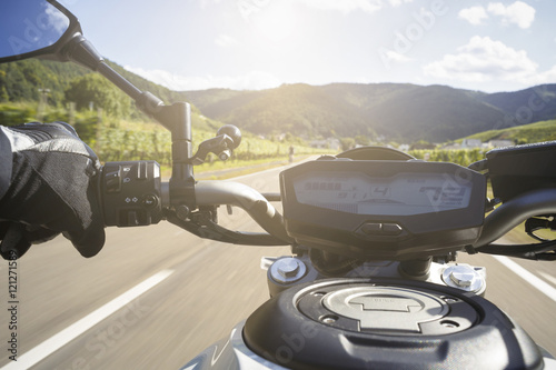 Motorradfahrer fährt auf Straße im Sommer photo