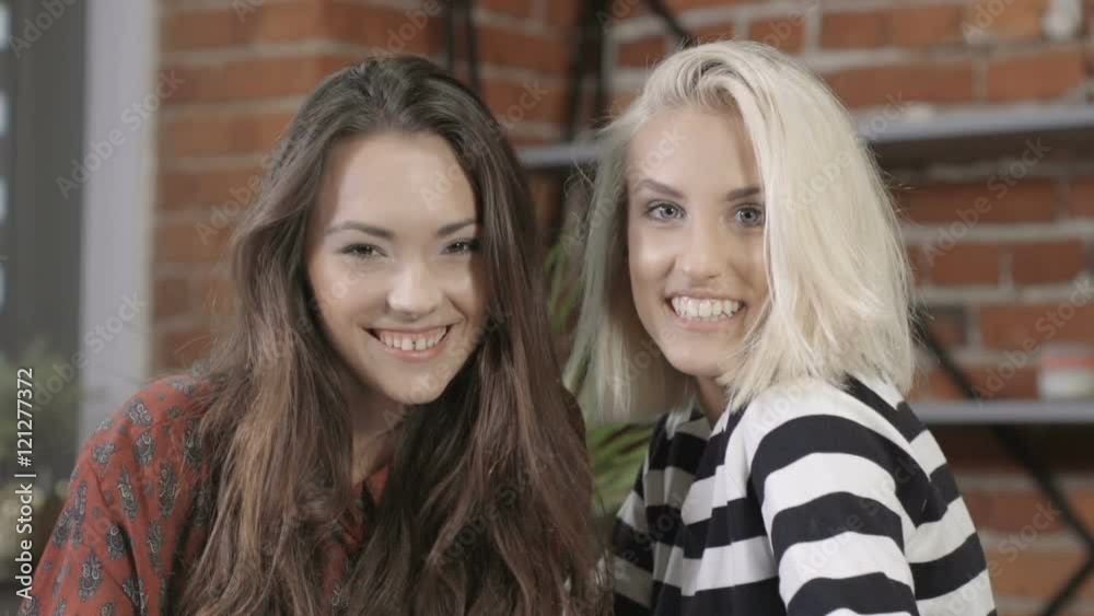 Two girls looking at camera and smiling at modern loft apartment. Two girls looking at camera and smiling at modern loft apartment.